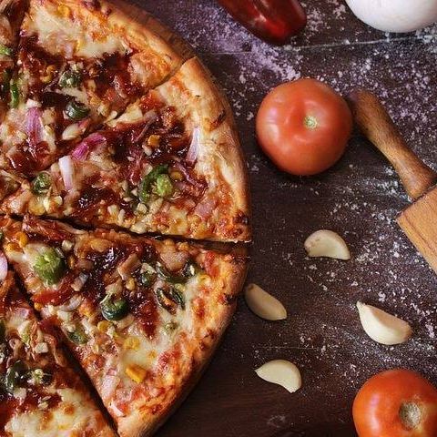 Pizza med tomater og kniv på bord